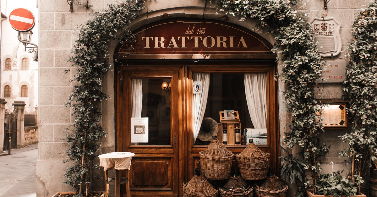 A large place to plant some berries - Exterior of cozy Italian restaurant with wooden door and entrance decorated with plants