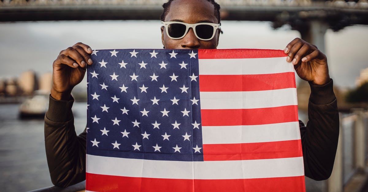 AC: Black Flag multiplayer functional? - Young friendly black man in sunglasses with bandana with US flag print in hands standing against blurred Brooklyn Bridge in New York City