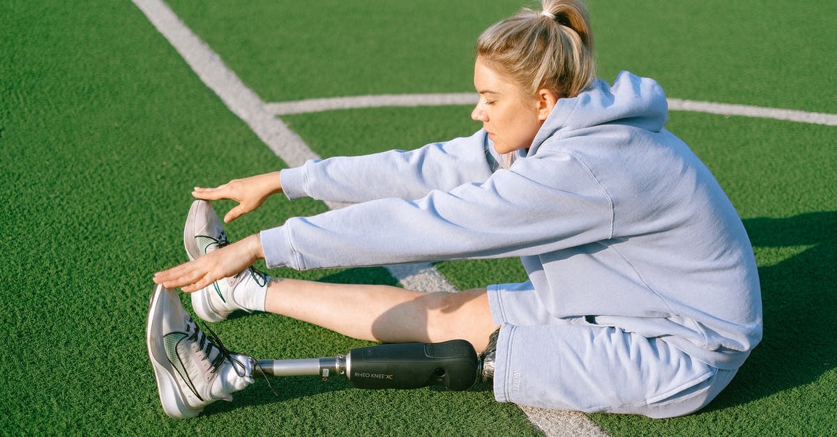 Aldrich's Inconsistent Physical Appearance? (possible spoilers) - Full body side view of handicapped female with leg prosthesis sitting on grassy sports ground while stretching body before training