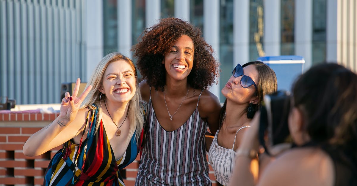 Any use to building up relationship with non party members? - Unrecognizable female photographer taking picture of cheerful young multiracial female friends smiling and showing V sign during party on modern building rooftop