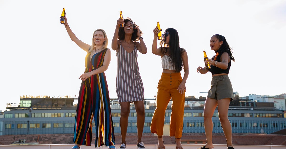 Any use to building up relationship with non party members? - Full body of happy young diverse girlfriends dancing and drinking beer while having fun together during open air party on building rooftop