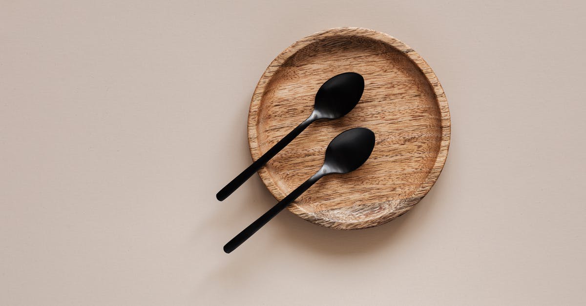 Are all agents identical except for their abilities? - Top view of composition of round wooden plate with smooth surface and similar black metal spoons on beige surface