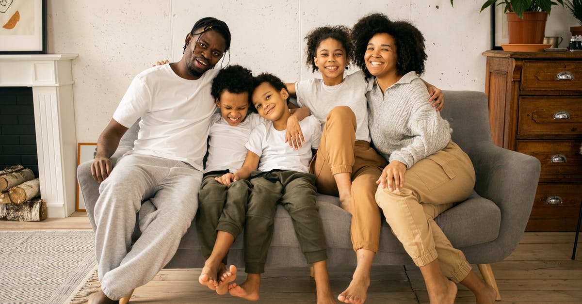 Are Ninten and Ness related in anyway in the Mother series? - Full body of cheerful African American parents with children looking at camera while sitting on sofa in room with fireplace