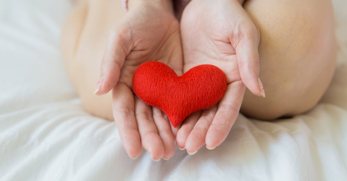 Are there any droids that heal - Unrecognizable female sitting with bare legs on white sheet with small red heart in hands in light room in daytime