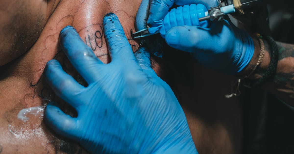 Are there special gun prefixes beyond Trick Shot? - High angle hands of anonymous tattooist in blue gloves using professional tool to make tattoo on back of client in salon