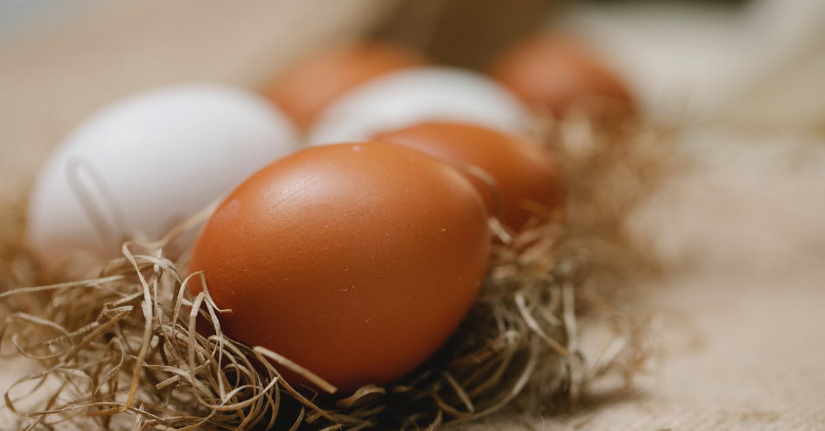 Brown Chickens and egg frequency - Fresh chicken eggs placed in straw on table with cloth in soft focus