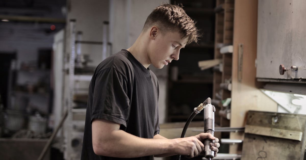 Can't assemble the pot, it keeps breaking - Side view of young male worker using pneumatic tool for handling detail in workshop