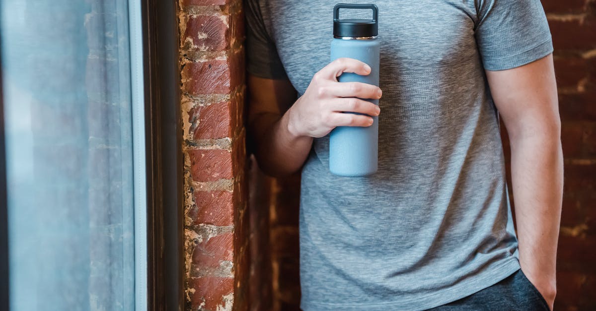 Can't collect Pokemon Go gym rewards - Unrecognizable muscular male in sportswear standing with hand in pocket near brick wall and window with bottle in hand in gym