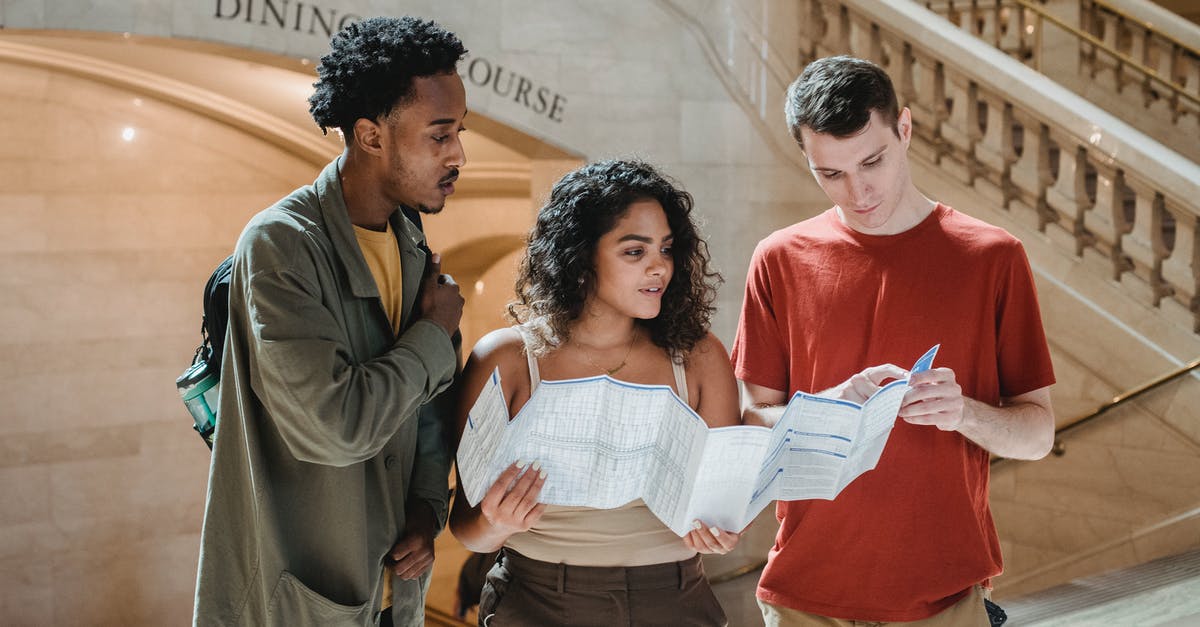 Can't find my maps in Minecraft - Focused young man pointing at map while searching for route with multiracial friends in Grand Central Terminal during trip in New York