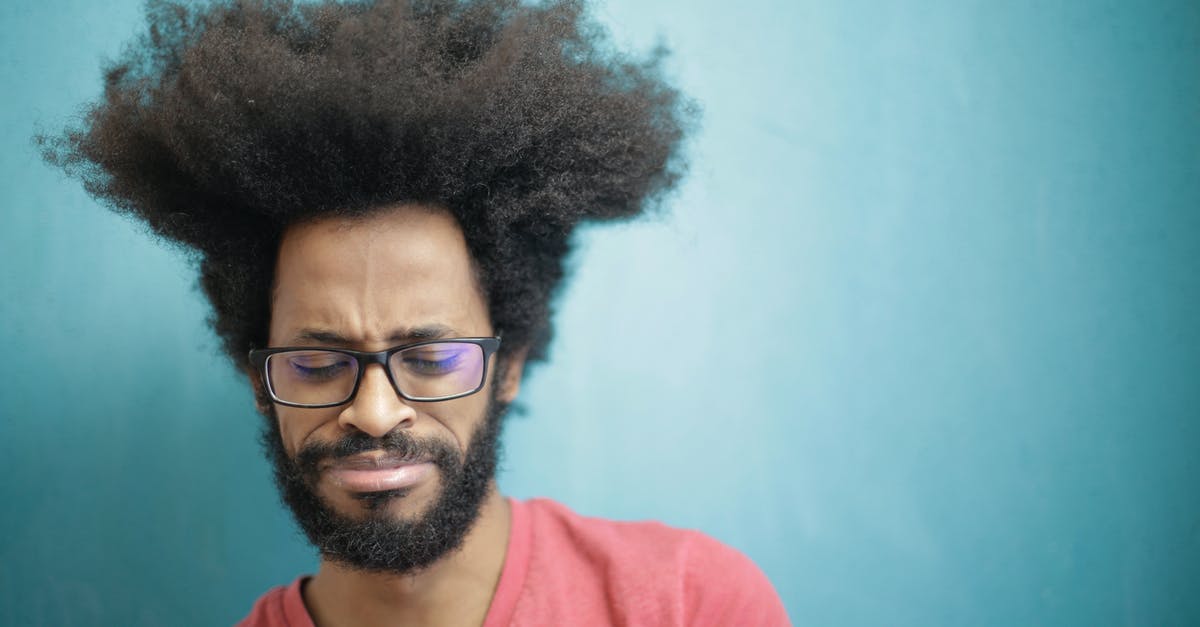 Can't get into 3rd puzzle - Young bearded ethnic male with creative Afro hairstyle wearing eyeglasses and pink t shirt looking down pensively thinking about trouble or question