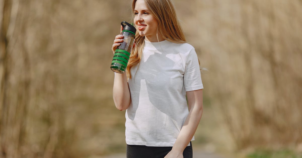 Can't run any program in - Smiling woman drinking water during training in park