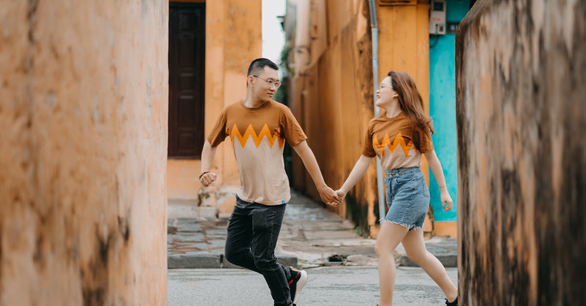 Can't run any program in - Positive stylish Asian couple running on old street of town