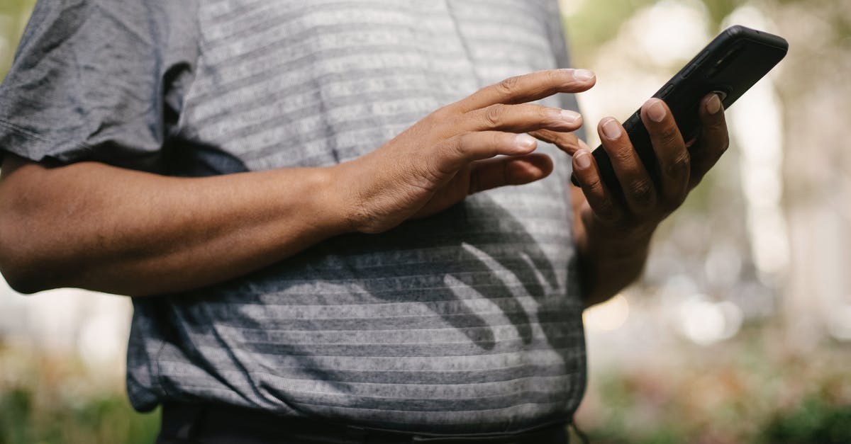 Can't send messages in Twitch Chat - Crop anonymous male in casual clothes using smartphone on blurred background of street