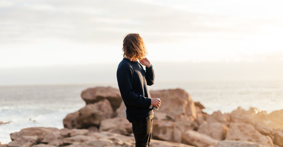 Can a province be considered neighbor if divided by a sea? - Side view of anonymous male traveler with can of beverage admiring ocean from rough rocks under shiny sky in evening Can a province be considered neighbor if divided by a sea? - Side view of anonymous male traveler with can of beverage admiring ocean from rough rocks under shiny sky in evening