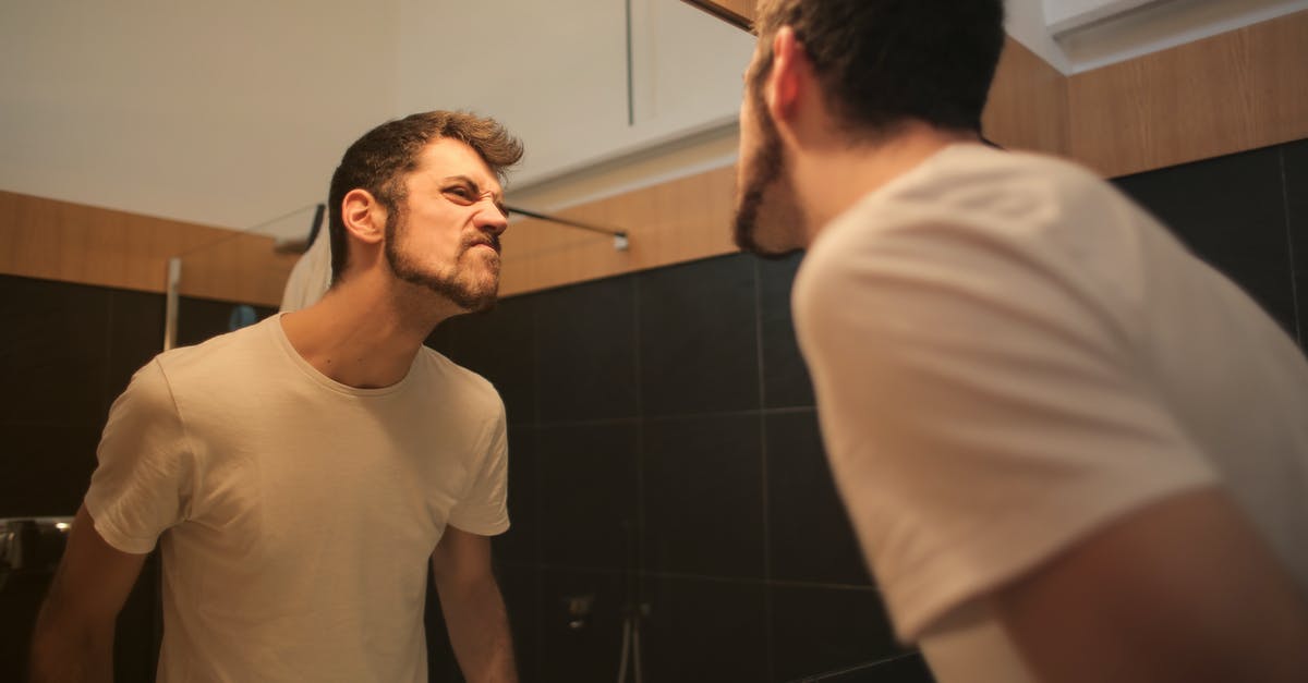 Can a roaming pokemon appear in the Battle Zone? - Low angle side view of young bearded male in casual shirt standing in bathroom and looking at with frown mirror in morning