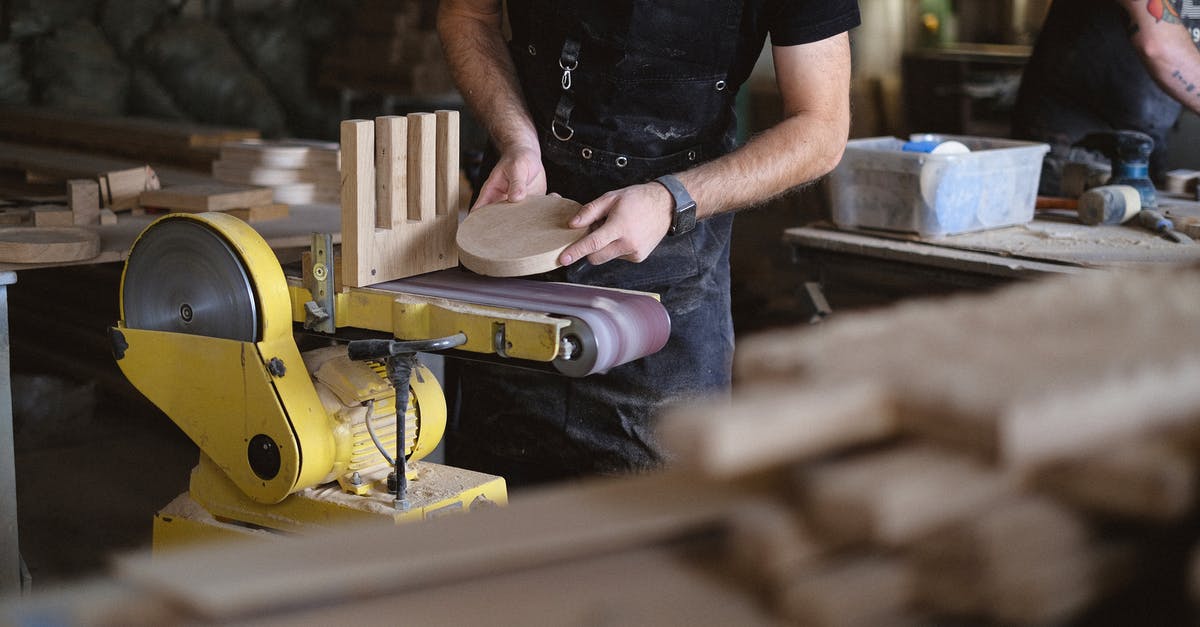 Can I find all the Tetra Master cards in Disc 4? - Unrecognizable male artisan using belt and disc sander to shape wooden detail while working near anonymous coworker in workshop with stack of wooden boards