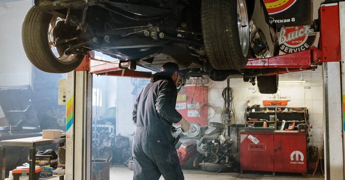 Can I get back an uninsured car? - Man in Blue Jacket and Gray Pants Standing Near Black Car