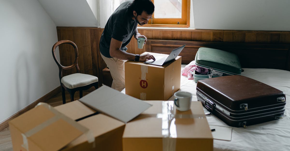 Can I move my new leaf save file to my computer? - Side view of ethnic male in casual clothes and wristwatch surfing internet on netbook and standing with cup of hot drink surrounded by cardboard boxes and suitcases in bedroom