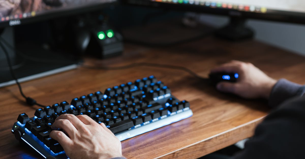 Can I play overwatch with a keyboard and mouse on Xbox? - High angle crop male in casual clothes sitting at desk and browsing contemporary computer while typing on backlit keyboard and using mouse