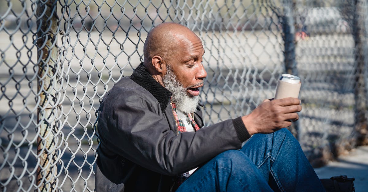 Can I remove an old Directx version - Side view of black homeless bald man sitting on street with beer can in hand and leaning on wire railing