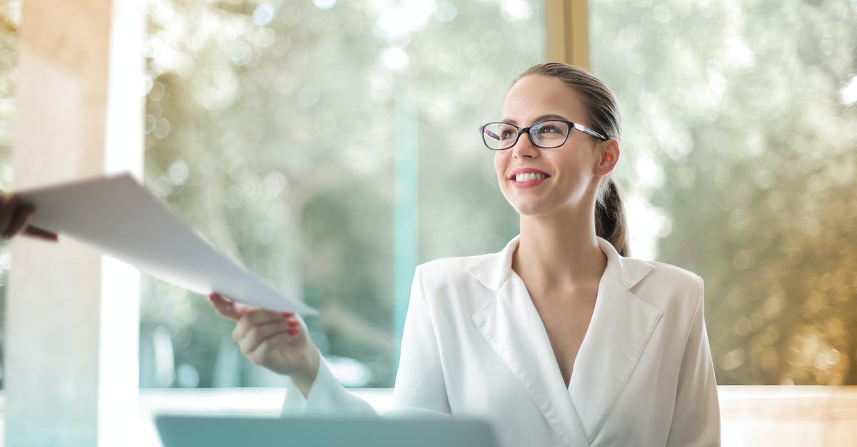 Can I share a character across devices - Low angle of successful female executive manager in classy style sitting at table with laptop in contemporary workplace and passing documents to colleague