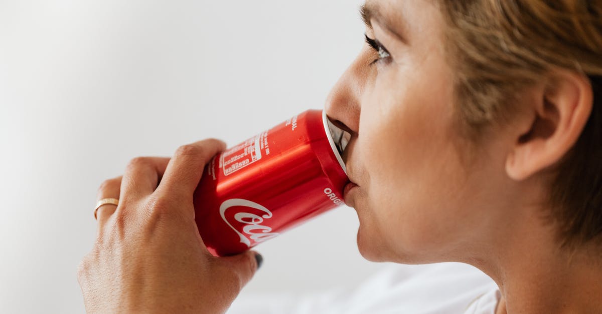 Can I undo red choices? - Side view of crop wistful female in casual wear and gold ring enjoying coke from red can while sitting near white wall and looking away