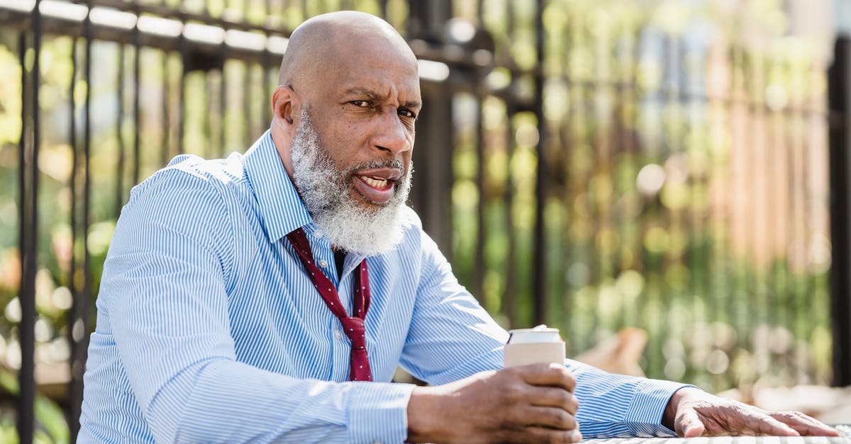 Can you break doors by throwing things at them? - Sullen black man sitting at table with drink