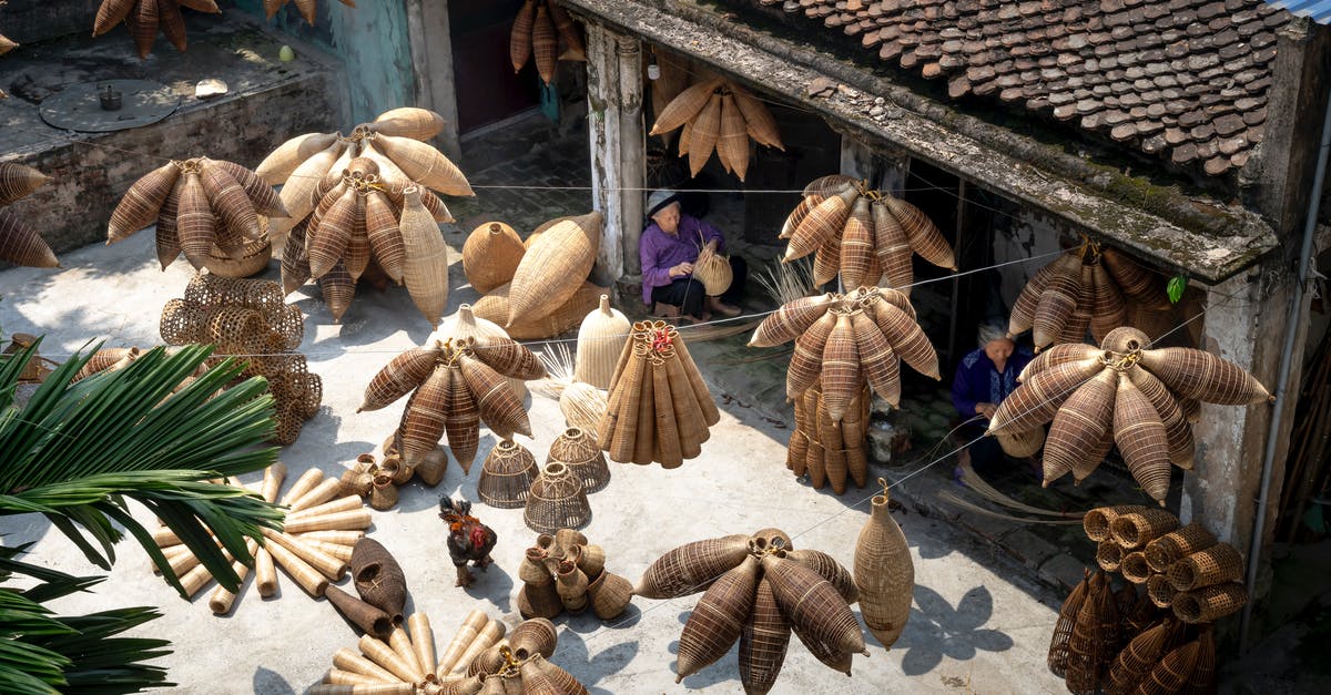 Can you make money from your settlements? - From above of people sitting and making bamboo fish traps while working on local bazaar in Vietnam in daylight