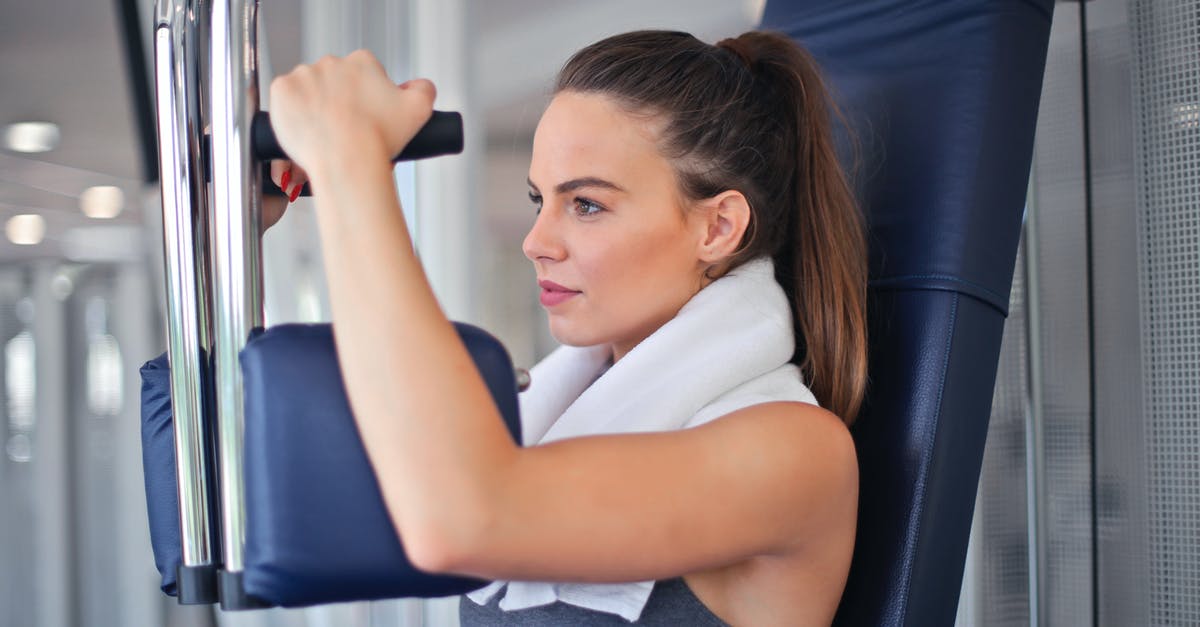 Chest contents leveling - Young determined sportswoman doing exercise on weight machine in modern sports club