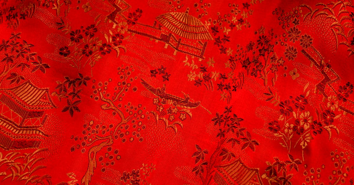 Clothing piece stuck behind creature part. (Spore) - Background of bright fabric with oriental design of tree and floral pattern with traditional huts elements on thick decorated textile