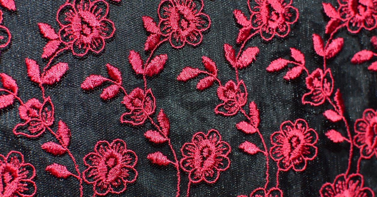 Clothing piece stuck behind creature part. (Spore) - Seamless background of creative flowers with leaves embroidered on black fabric with red thread creating symmetrical pattern on thick textile