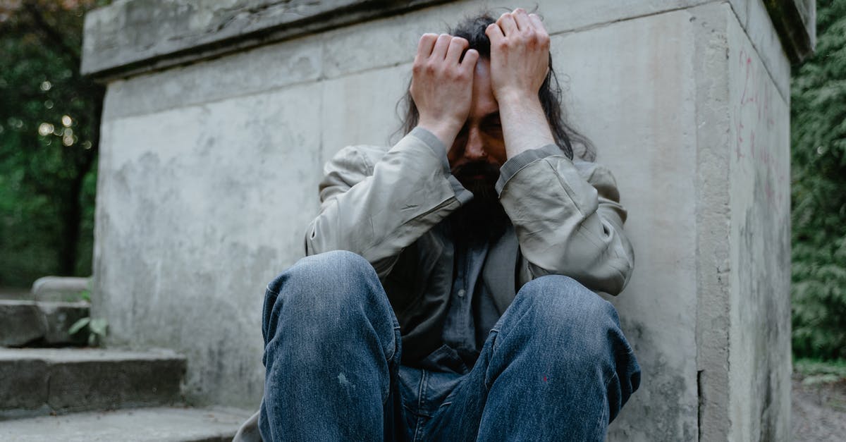 Conserving hunger while running? - A Man in Denim Jeans Sitting on the Street with His Hands on His Head