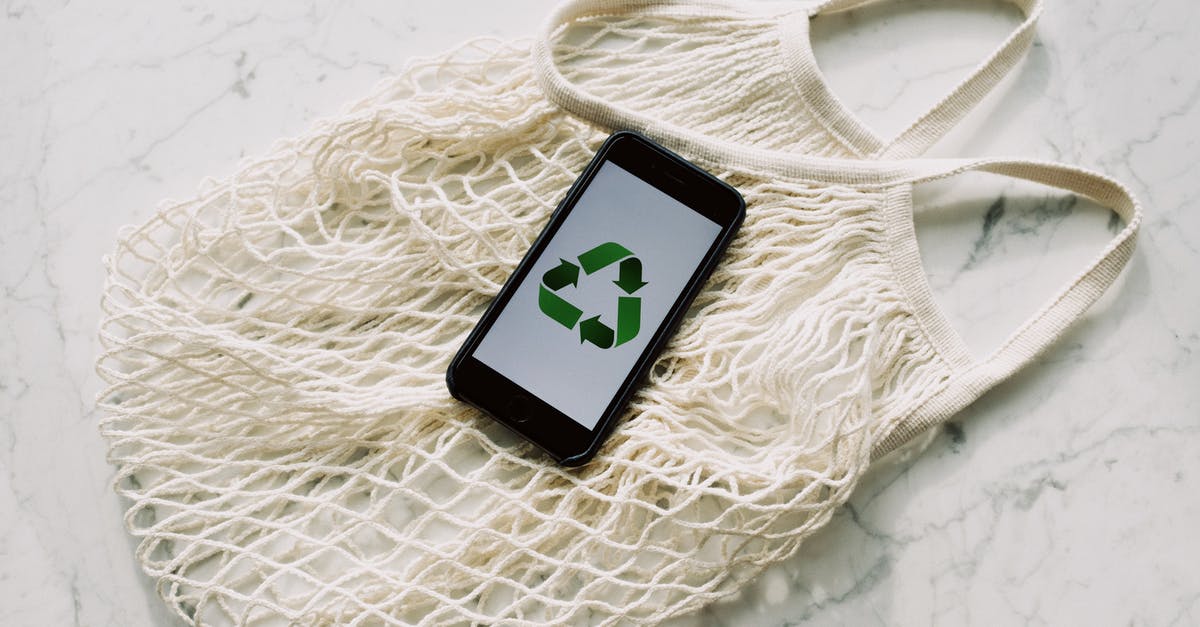 Convert PS3 save to PS4? - Overhead of smartphone with simple recycling sign on screen placed on white eco friendly mesh bag on marble table in room