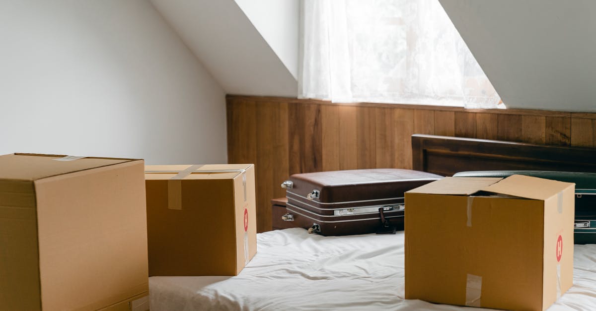 Copy and change item names in chest - Small cardboard boxes and leather cases placed on bed with sheet near big box in light room of house under sloping roof