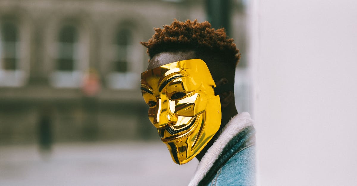 Corruption on hardmode - Black activist in golden Anonymous mask standing on city street