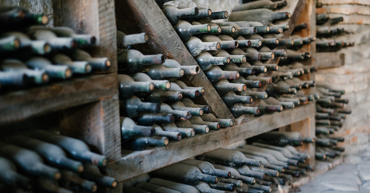 Craftbook - Sort Potions - Dusty alcoholic beverage bottles with coiled corks on wooden shelves at wine farm