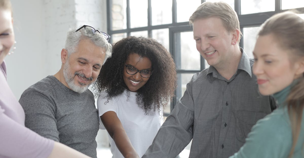 Discord-Minecraft integration - Happy diverse colleagues joining hands at work in afternoon