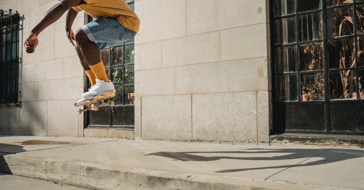 Do jump stunts benefit you? - Crop faceless black man jumping on skateboard on street