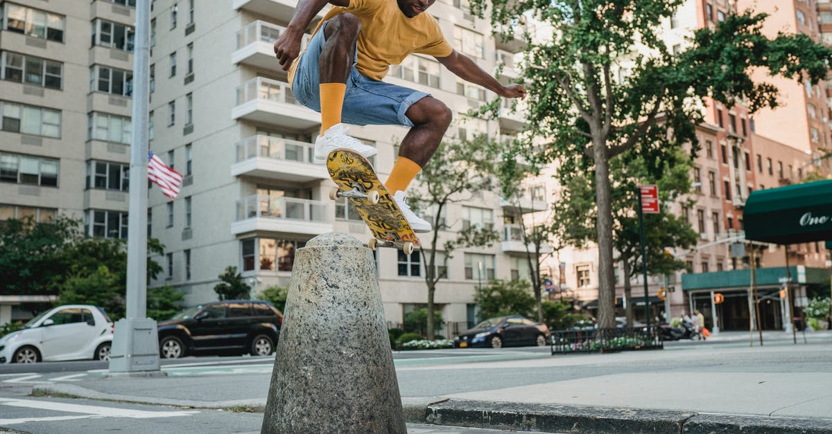 Do jump stunts benefit you? - Full body athletic African American male skater in summer wear jumping on skateboard on urban street