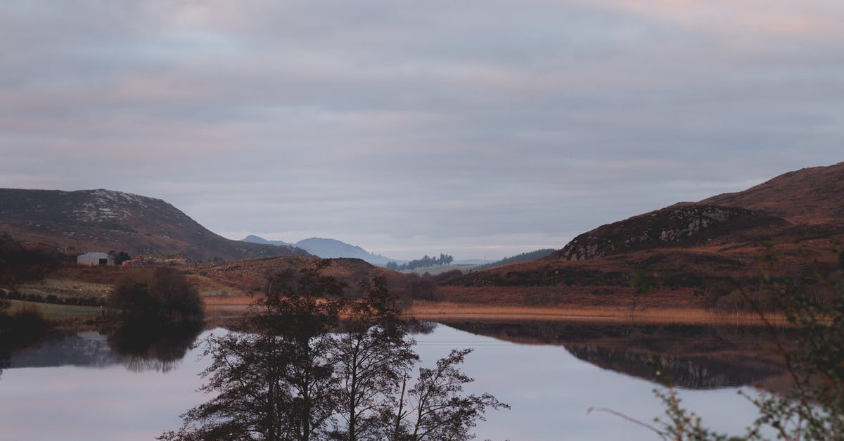 Do multiple land claim blocks still prevent zombie spawning? - Tranquil scenery of pond surrounded by rocky hills and rare trees against cloudy overcast sky in quiet evening