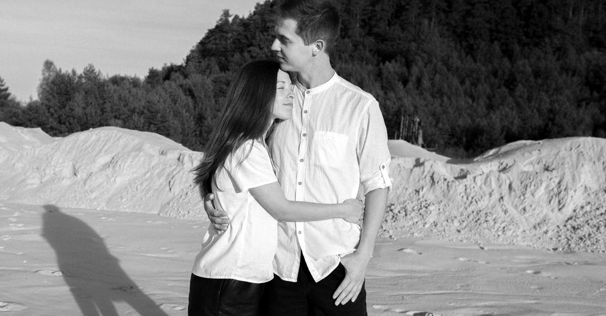 Do quays affect land value - Black and white of young glad woman with closed eyes embracing boyfriend on dry terrain with shadow in sunlight