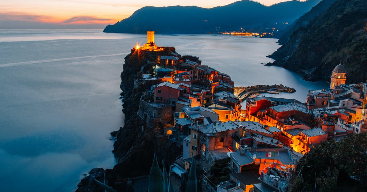 Do settlements even matter? - Amazing landscape of small village with illuminate ancient tower and colorful buildings located on rocky cliff in front of sea in Italy