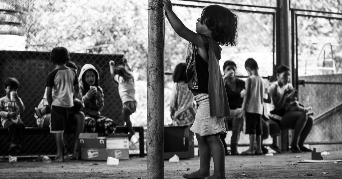 Do you need to fence in your animals? [duplicate] - Black and white side view full body of barefoot poor ethnic boy standing near metal pole among people eating food