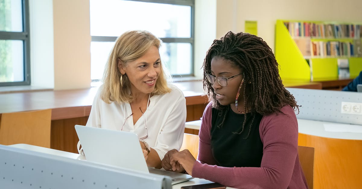 Does a higher tickrate actually help in fast paced online FPSs? - Positive adult female teacher explaining task to young black student with Afro braids doing assignment on laptop in modern classroom