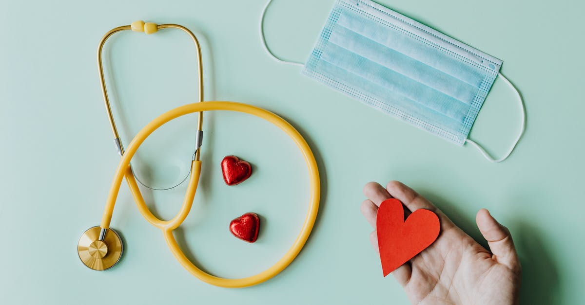 Does armor prevent injury? - Top view of crop anonymous person hand with red paper heart on table with stethoscope and medical mask for coronavirus prevention