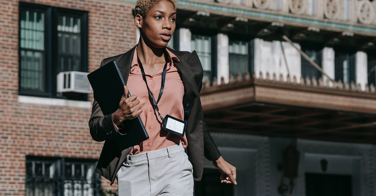 Does Miitomo run on Samsung phones? - Confident African American female entrepreneur in classy outfit with badge carrying laptop while running fast on street