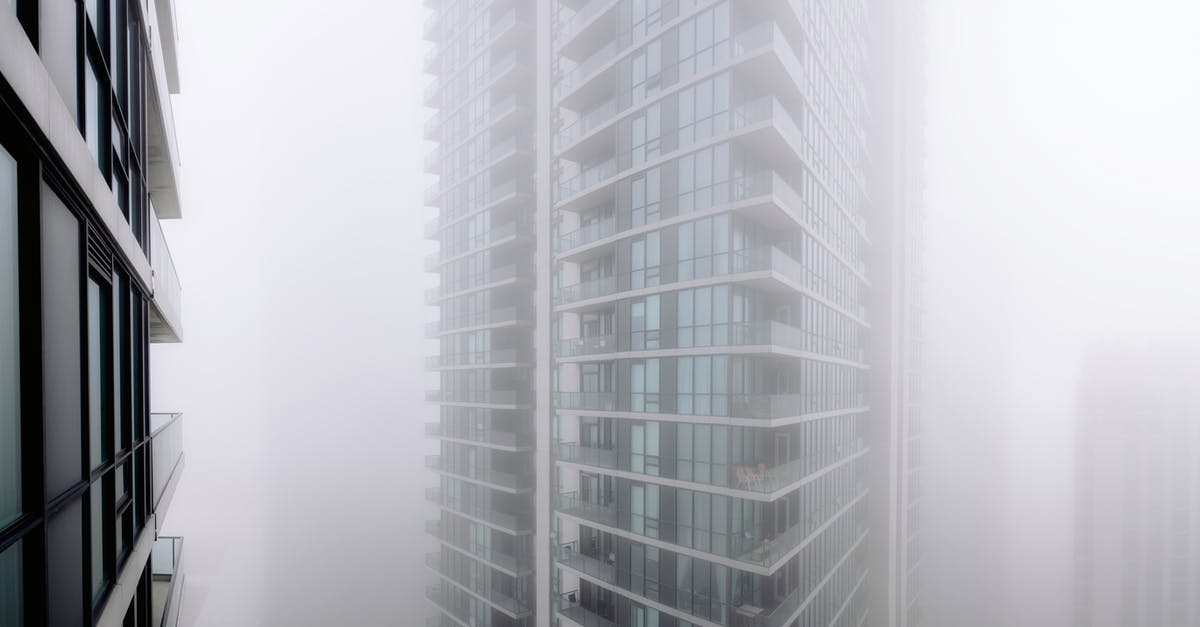 Does mirage go invisible if reviving himself? - Contemporary residential building with balconies covered with thick fog located on street of modern city with houses in overcast weather