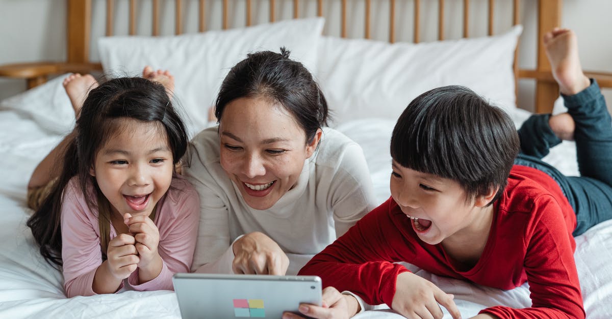 Does My Nintendo have a point cap? - Full body happy Asian mother pointing at screen tablet showing interesting information to cheerful kids while lying on cozy bed in light room