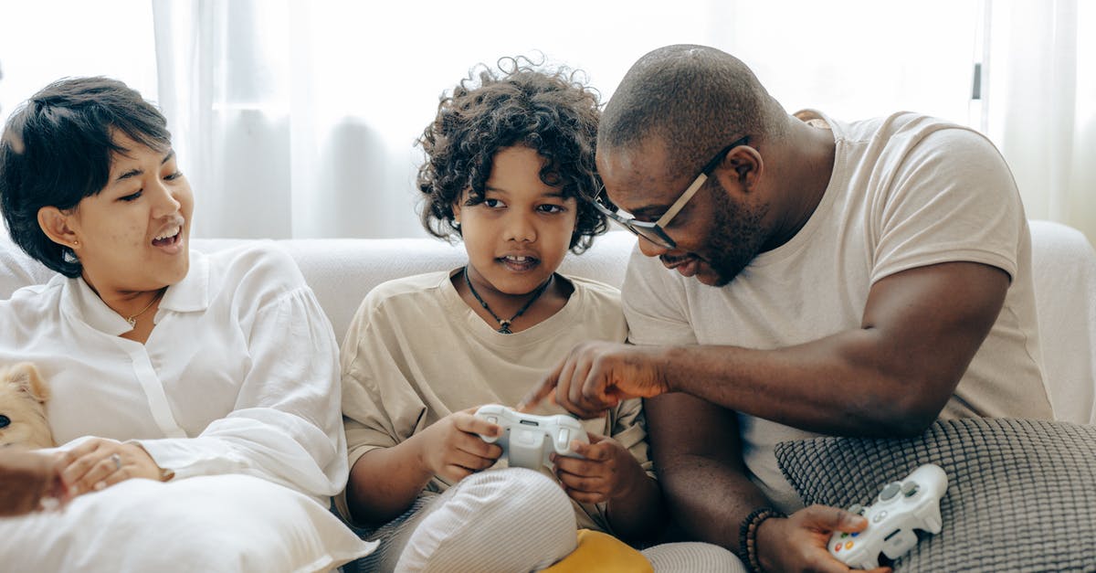 Does My Nintendo have a point cap? - Concentrated black father pointing on joystick buttons explaining rules of playing to son while positive mother watching process