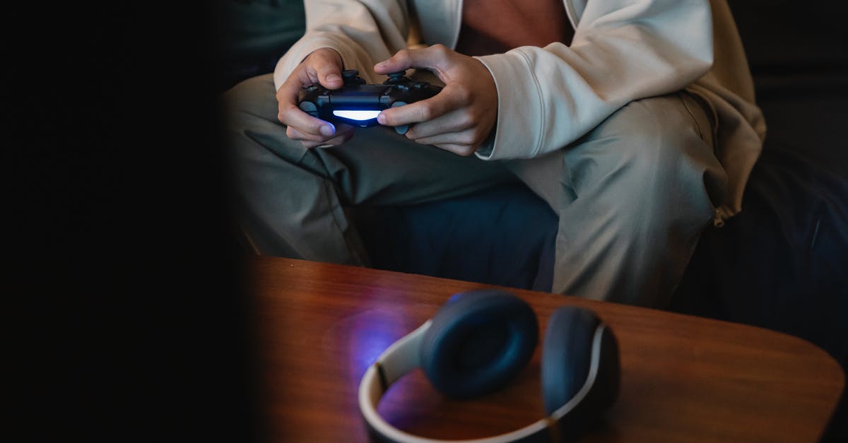 Does Pokémon GO have any interoperability with handheld Pokémon games? - Crop unrecognizable man with joystick playing video game while sitting against table with modern headset in house room